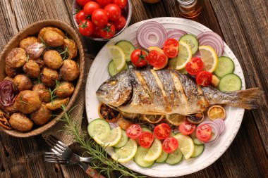 Kavrulmuş patates ve sebze plaka üzerinde ızgara balık