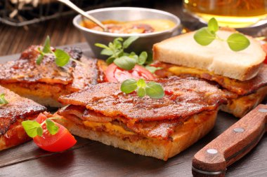 Kızarmış domuz pastırması ve ahşap zemin üzerine bira ile sandviç