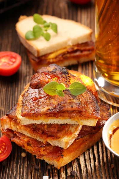 Sandwich cu slănină prăjită și bere pe fundal din lemn — Fotografie, imagine de stoc