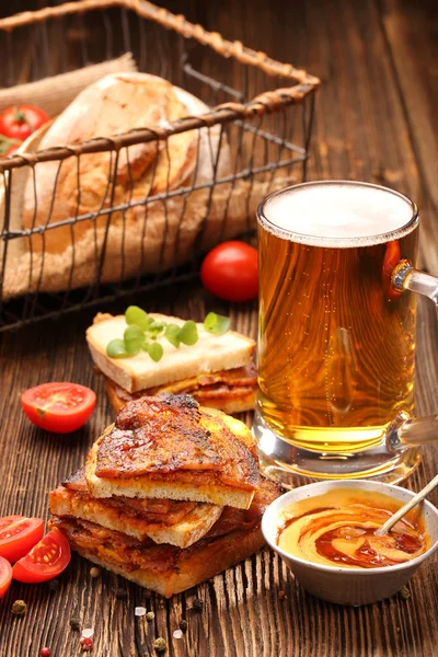 Σάντουιτς με τηγανητό μπέικον και μπύρα σε ξύλινο φόντο — Φωτογραφία Αρχείου