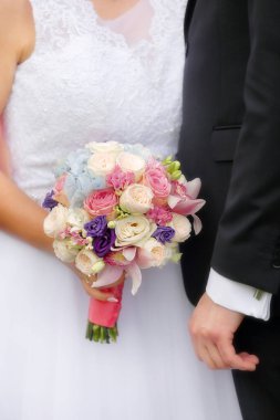 Gelin ve kocanın ellerinde bir buket gül. Parlak ışığın yanında ve mesaj için boş bir alan.