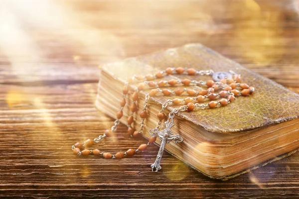 Rosary and prayer book on a wooden background and empty space for text