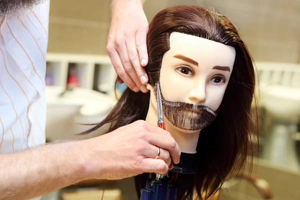 Barber student trimming brown hair using puppet and scissors — Stock Photo, Image