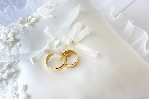 Anillos de boda de oro en una almohada con cintas — Foto de Stock