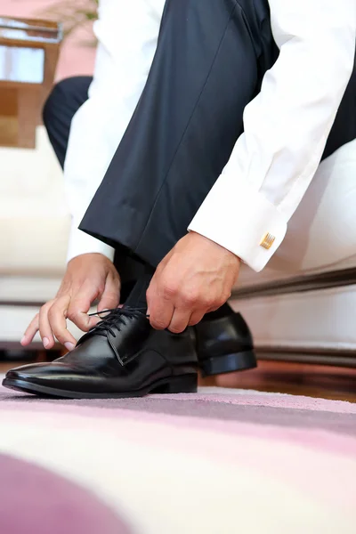 Groom dresses and binds shoes before the wedding — Stock Photo, Image