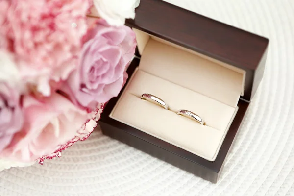 Anillos de oro blanco de boda en una caja en el ramo nupcial backgrou — Foto de Stock