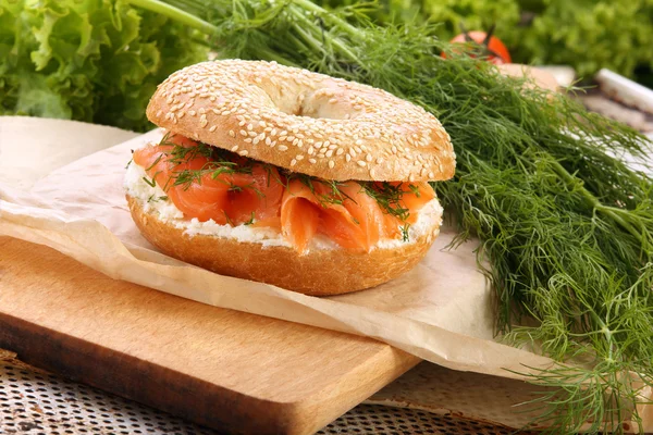 Sanduíche com salmão defumado e endro em uma tábua de cortar — Fotografia de Stock