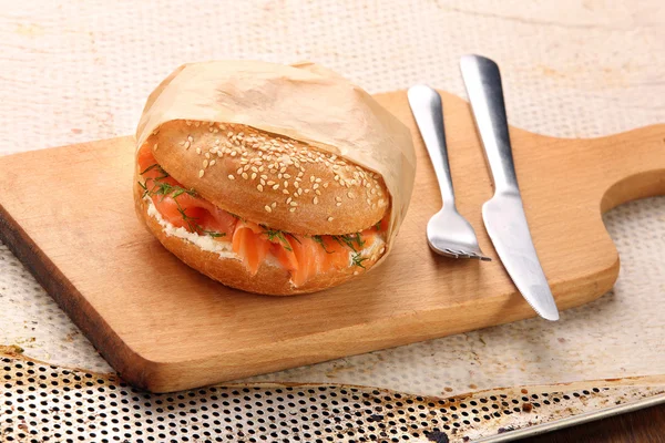 Sandwich with smoked salmon and dill wrapped in baking paper on — Stock Photo, Image