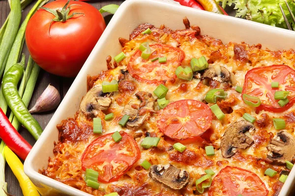 Auflauf mit Tomaten und Pilzen auf einem hölzernen Hintergrund — Stockfoto