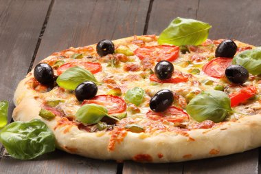Domates, zeytin ve fesleğen ahşap arka plan üzerinde pizza