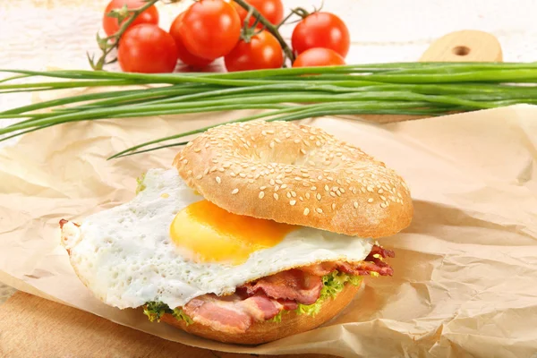 Panino con pancetta fritta e uovo su un tagliere — Foto Stock