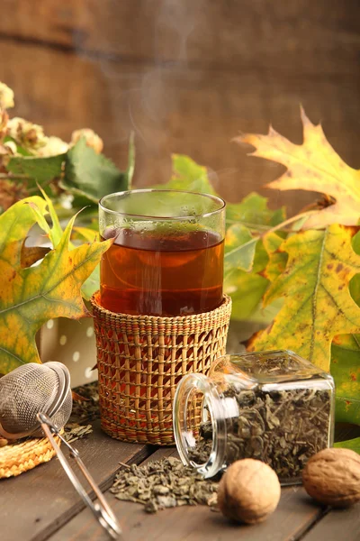 Té verde caliente en un vaso sobre un fondo de madera con hoja de otoño — Foto de Stock