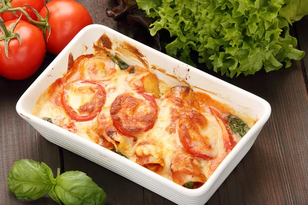 Cannelloni baked in a roasting pan on a wooden background — Stock Photo, Image