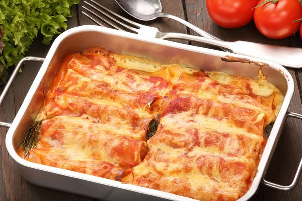 Cannelloni baked in a roasting pan on a wooden background — Stock Photo, Image