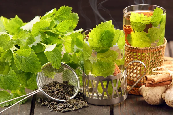 Té verde caliente en un vaso sobre un fondo de madera con bálsamo de limón — Foto de Stock