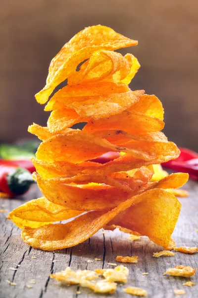 Paprika chips with chili peppers on a wooden background — Stock Photo, Image