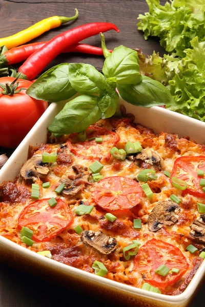 Auflauf mit Tomaten und Pilzen auf einem hölzernen Hintergrund — Stockfoto