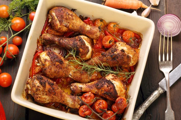 Geroosterde kip drumsticks met groenten in een pan op een houten Rechtenvrije Stockfoto's