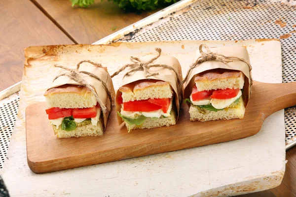 Focaccia sandviç mozzarella fesleğen ve bir doğrama üzerinde domates ile