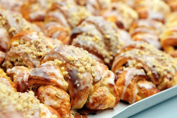 Croissants with sweet icing and walnuts in a bakery — Stock Photo, Image