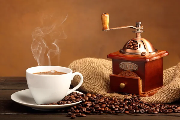 Black coffee in white cup with smoke and coffee grinder — Stock Photo, Image