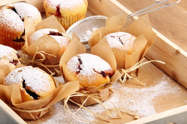 Muffins con mermelada espolvoreado con azúcar en polvo en bandeja de madera — Foto de Stock