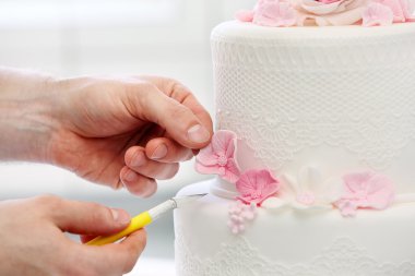 Confectioner decorates wedding cake clipart