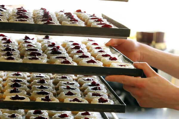 Pastelero pone pasteles en la panadería —  Fotos de Stock