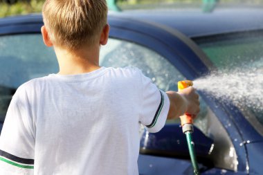 Genç çocuk hortumu ile araba yıkama
