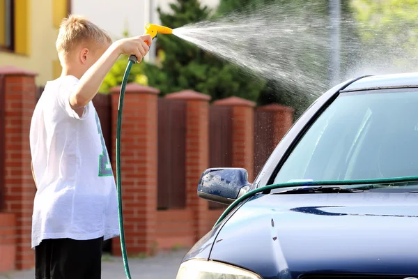 Young boy washing the car with hose — Stock Photo, Image