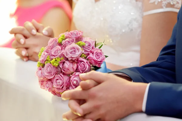 Nygifta med bröllop ros bukett på kyrkan — Stockfoto