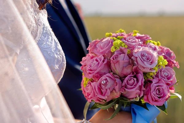 Nygifta med bröllop ros bukett utomhus — Stockfoto