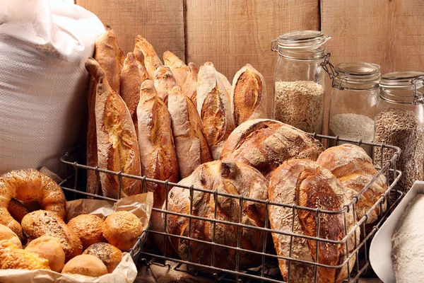 Φρέσκο ψωμί σε μεταλλικό καλάθι στο φούρνο, σε ξύλινη φόντο — Φωτογραφία Αρχείου