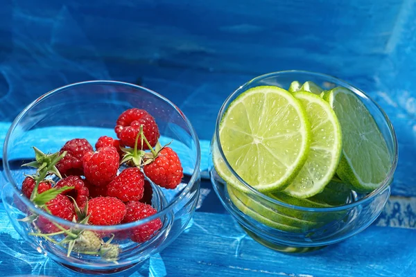 Framboesas frescas e limão em um frasco no fundo azul — Fotografia de Stock