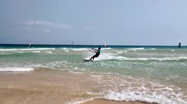 İspanya, Sotavento, Fuerteventura - 04.08.2025: Sotavento sahilinin panoramik manzarası ve uçurtmacılar ve rüzgar sörfçüleri güçlü rüzgarlarda yelken açarlar, Fuerteventura, Kanarya Adaları, İspanya.