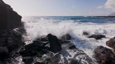 Tenerife Adası 'nın kayalık sahillerinde ağır çekimde köpüklü deniz dalgalarının panoramik görüntüsü, Kanarya Adaları, İspanya.