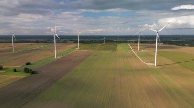 Öğleden sonra güneşi altında elektrikli yel değirmenleri olan büyük tarlaların havadan görünüşü