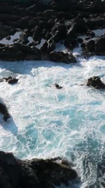 Los Gigantes, Tenerife, Kanarya Adaları, İspanya 'nın kayalık sahillerinde köpüklü deniz dalgalarının dikey görüntüsü.