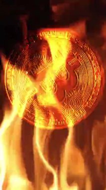 Bitcoin kırmızı alevlerin arkaplanına karşı yavaş çekimde döner, bu da ısınmış bir pazar veya finansal değerde ciddi bir düşüş, yavaş çekim dikey görünümü ve metin alanı için kopyalama alanını gösterir