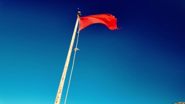 Sahilde dalgalanan kırmızı bayrak, dalgalı denizi ve banyo yasağını simgeliyor..