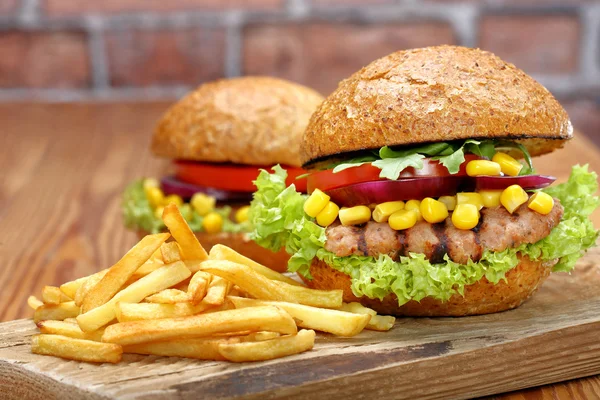Hamburger grillé avec frites, tomate, oignon et maïs sur bois b — Photo