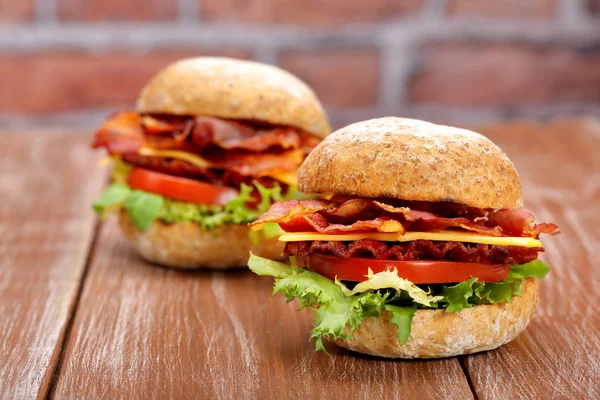 Hamburguesa de tocino con tomate y queso sobre mesa de madera —  Fotos de Stock