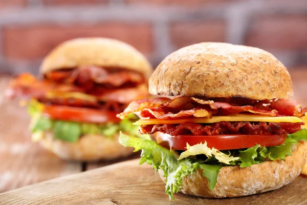 Hamburguesas de tocino con tomate y queso sobre mesa de madera —  Fotos de Stock