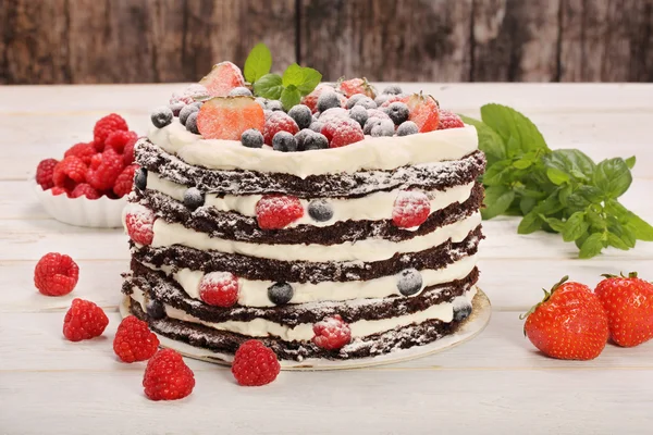 有木制黑色白色奶油和新鲜水果巧克力蛋糕 — 图库照片