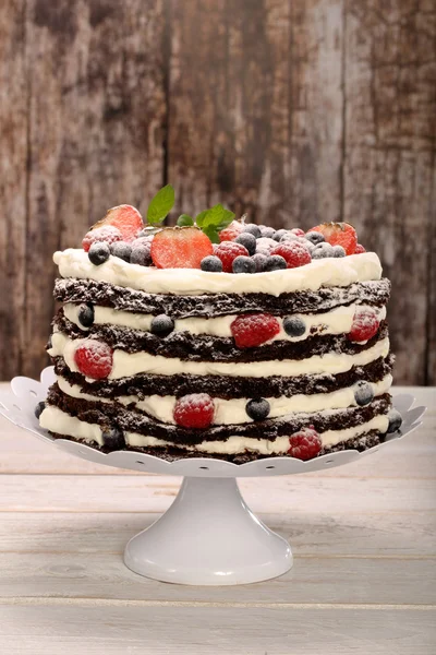 Ciasto czekoladowe z biały krem i świeże owoce na drewniane backg — Zdjęcie stockowe