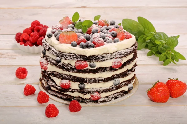 有木制黑色白色奶油和新鲜水果巧克力蛋糕 — 图库照片