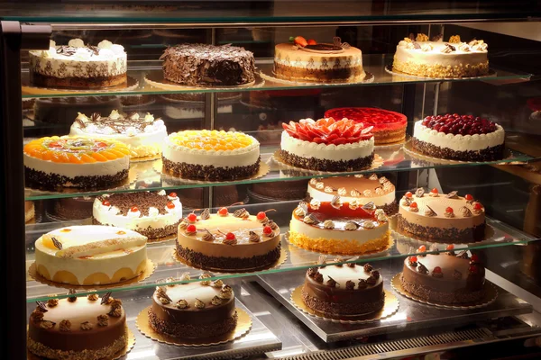 不同类型的蛋糕在糕点店玻璃显示 — 图库照片