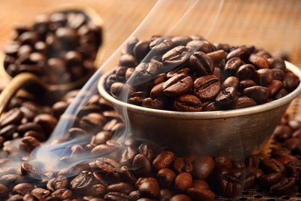 La fumée s'élève au-dessus des grains de café et du bol dans un style vintage — Photo