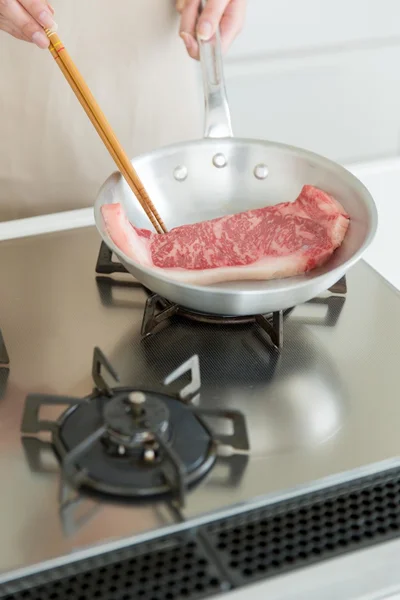 Frau bereitet Steak zum Abendessen zu Stockbild