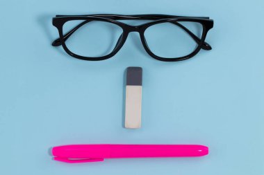 Mavi arka plan eğitim konsepti üzerine gözlük silici ve kalem. soyut yüz.